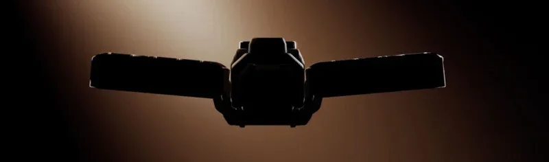 A dark, backlit silhouette of a mechanical device with two wide, rectangular wings extending from a central body.