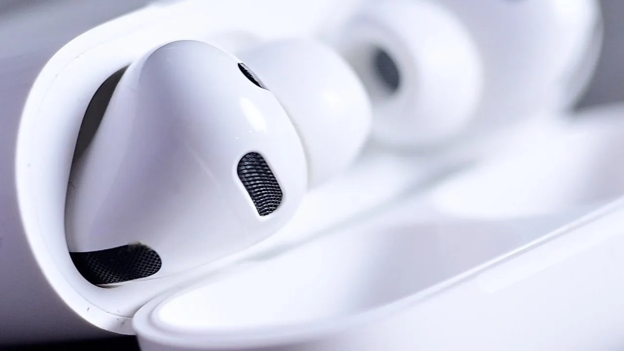 Close-up of white wireless earbuds resting in an open charging case, highlighting smooth plastic surfaces and small black speaker grilles
