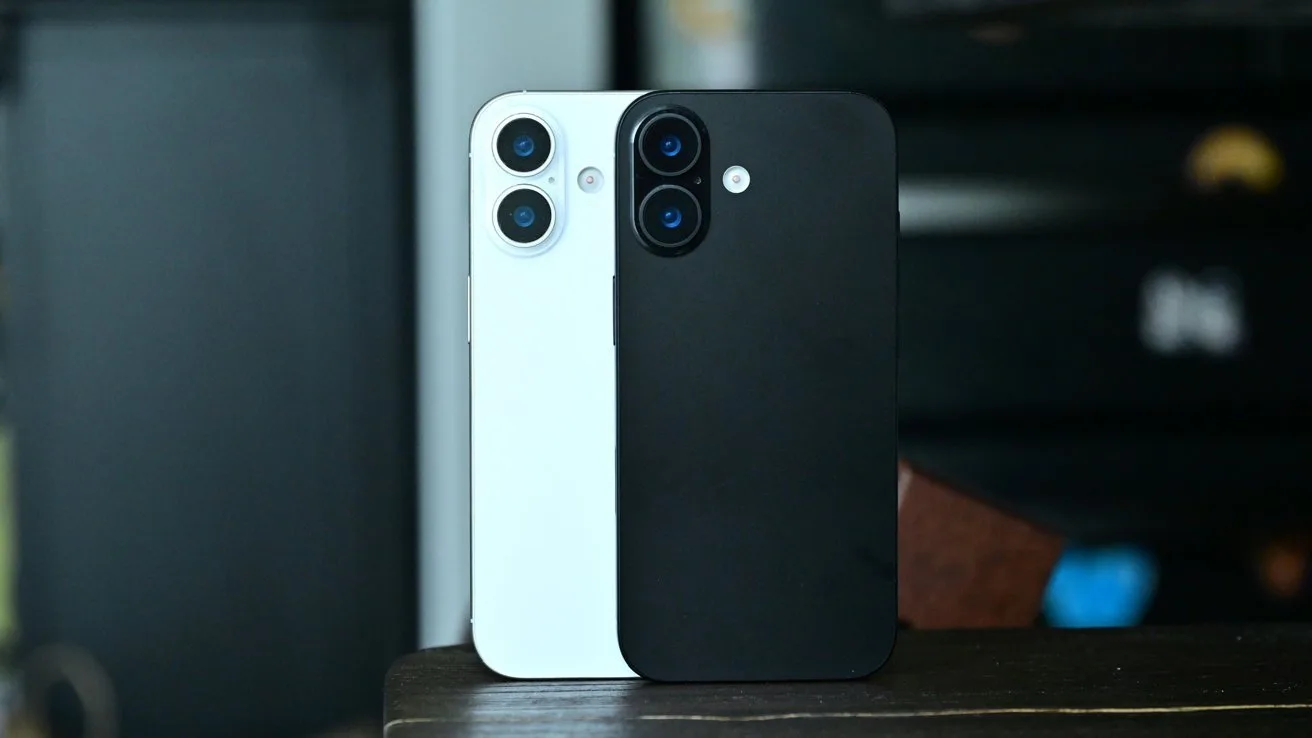 Two modern smartphones standing upright on a table, one white and one black, both showing their backs with dual rear cameras, against a softly blurred indoor background