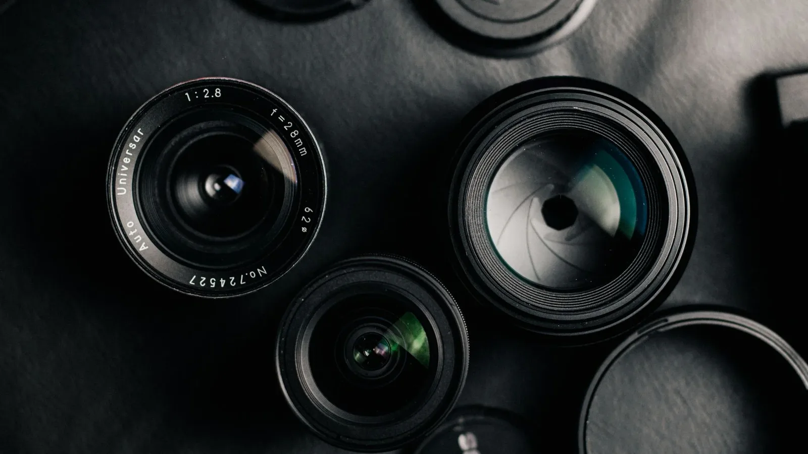 A collection of camera lenses arranged on a surface showcasing different focal lengths and apertures.