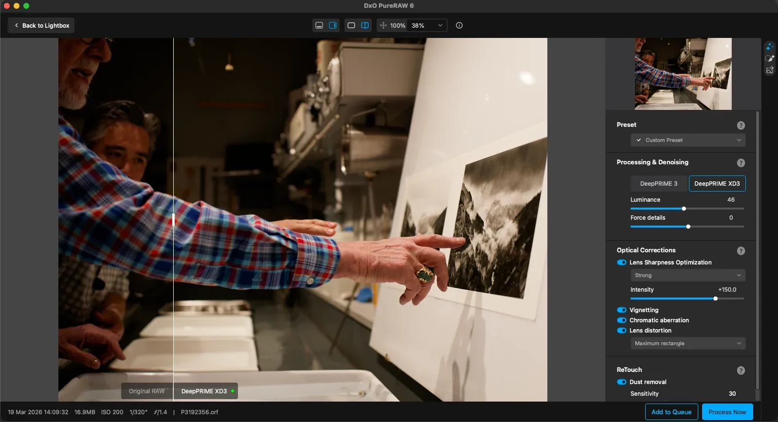 A person points at a black-and-white mountain photograph on a table in a workspace, while another observes; editing software interface with image adjustments is visible on the right side of the screen.