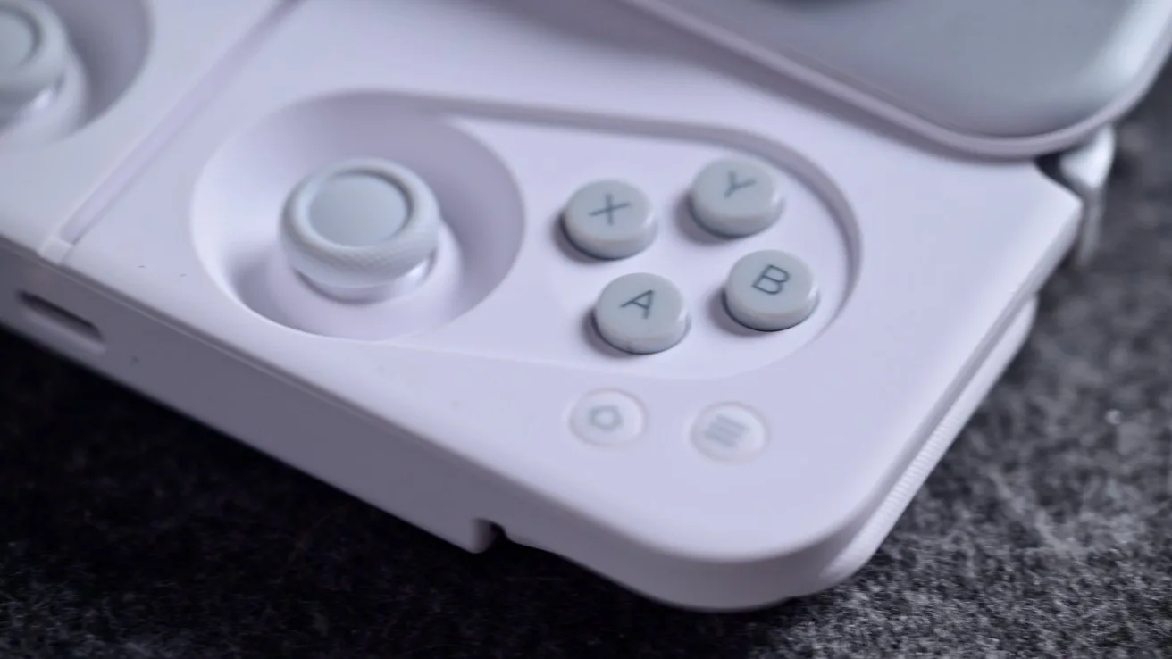 Close-up of a white gaming controller's right side, featuring a joystick and four circular buttons labeled X, Y, A, B on a textured dark surface.