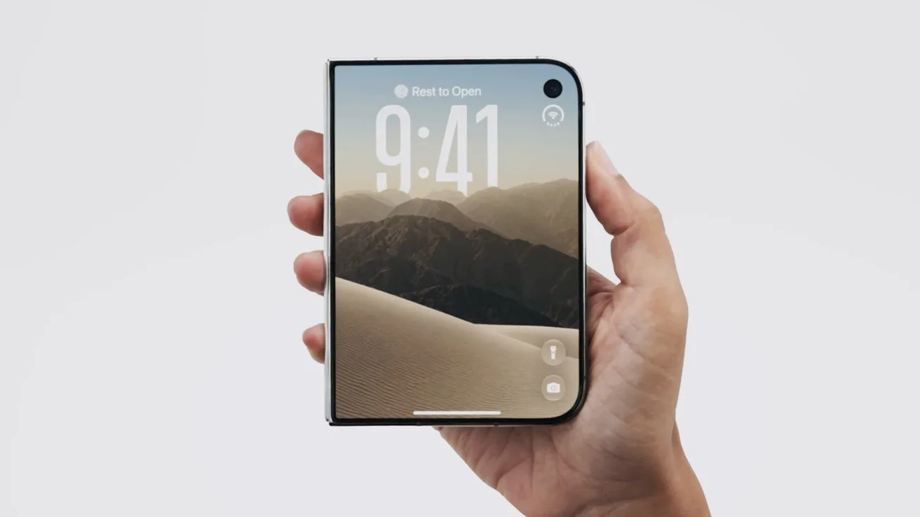 Hand holding a foldable iPhone Duo, displaying a lock screen with 9:41 time and a desert mountain landscape wallpaper on a light gray background