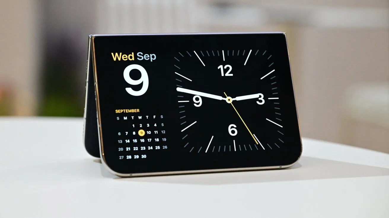 iPhone Duo showing an analog clock with white hands on a black face, next to a monthly calendar and weekday date, resting on a smooth white surface indoors