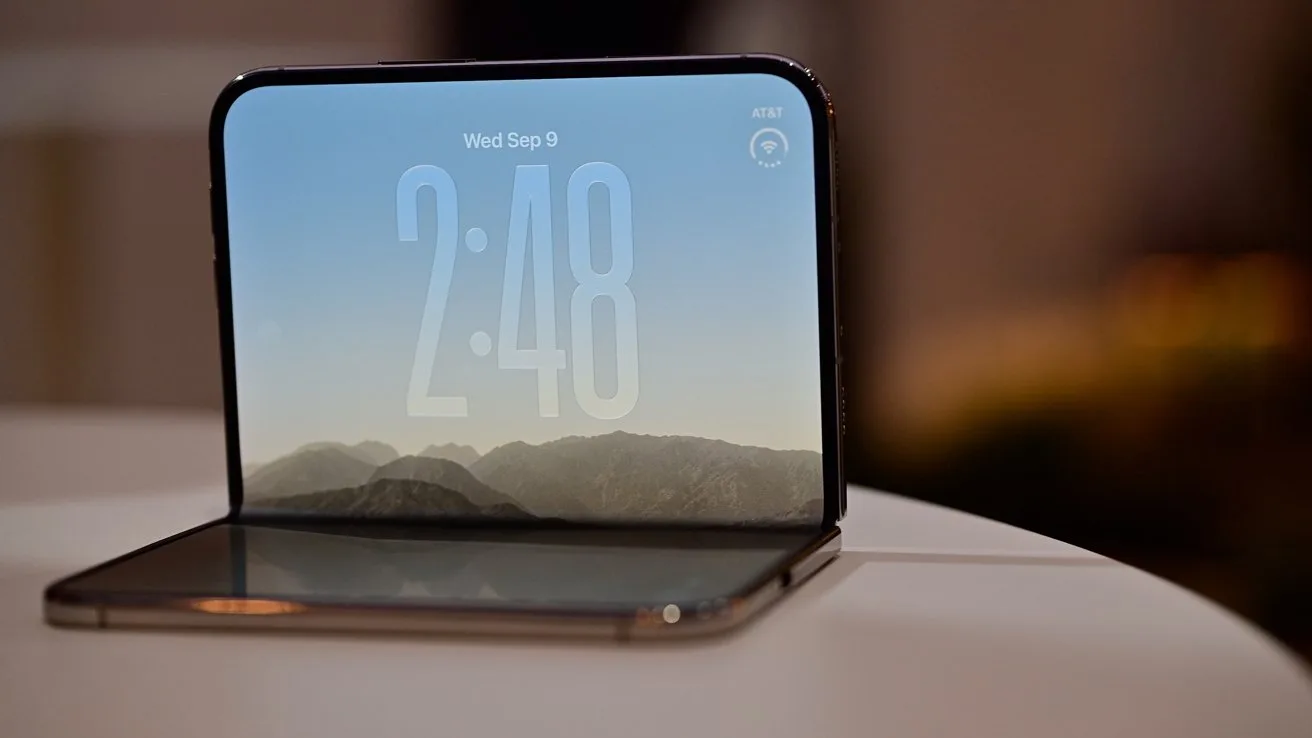 Foldable smartphone partially open on a table, displaying a large digital clock over a mountain landscape wallpaper, with soft indoor lighting in the blurred background
