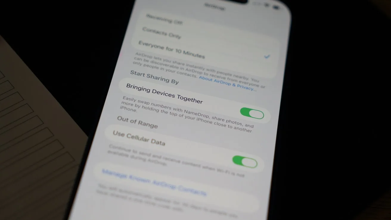Smartphone screen displaying settings, with options like Bringing Devices Together and Use Cellular Data, shown as green toggles, on a slightly angled phone resting on a dark surface