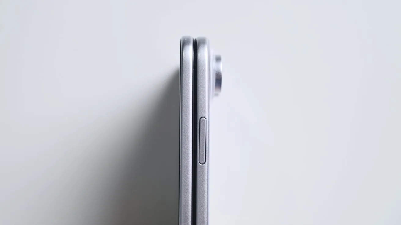 Side view of a closed silver smartphone on a light background, showing its thin profile, side button, and slightly protruding rear camera module