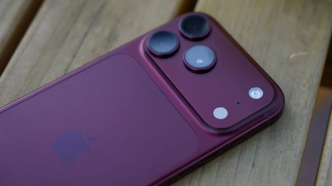 iPhone 18 Pro Max lying on a wooden surface, showing the back with three large rear camera lenses, flash, and Apple logo visible on the smooth metal finish