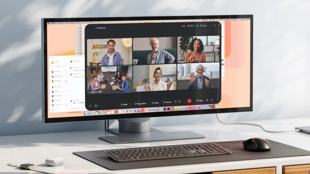 Ultrawide monitor on a desk showing a video conference with six people in separate windows, with keyboard, mouse, and minimal office accessories arranged neatly in front