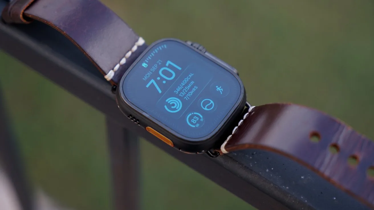 Apple Watch Ultra 4 with a dark screen showing 7:01 and fitness icons, attached to a brown leather band, resting on a metal railing with a blurred green background
