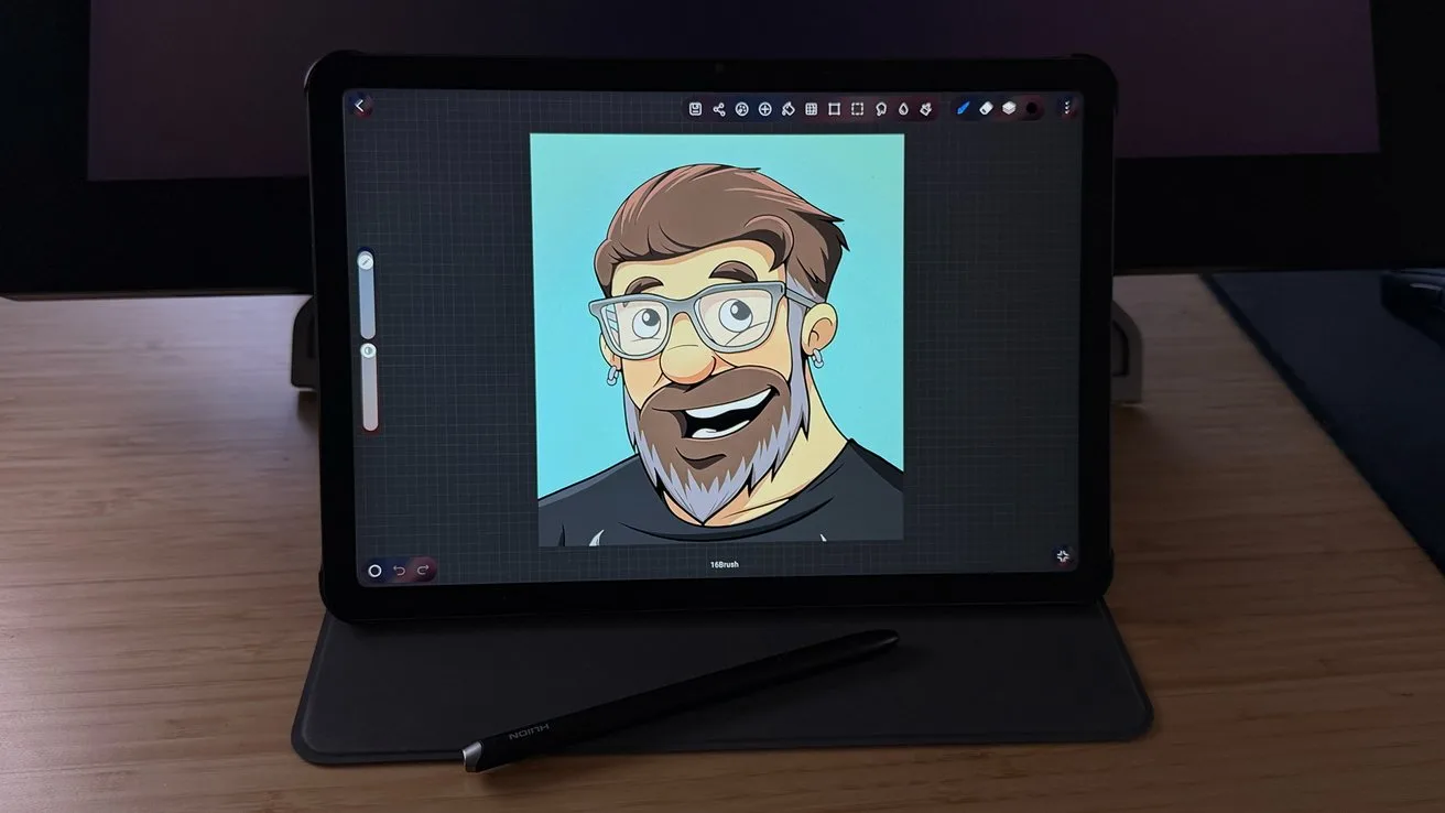 Tablet on a desk displaying a colorful cartoon portrait of a smiling bearded man with glasses, with a stylus resting in front of the device on a wooden surface