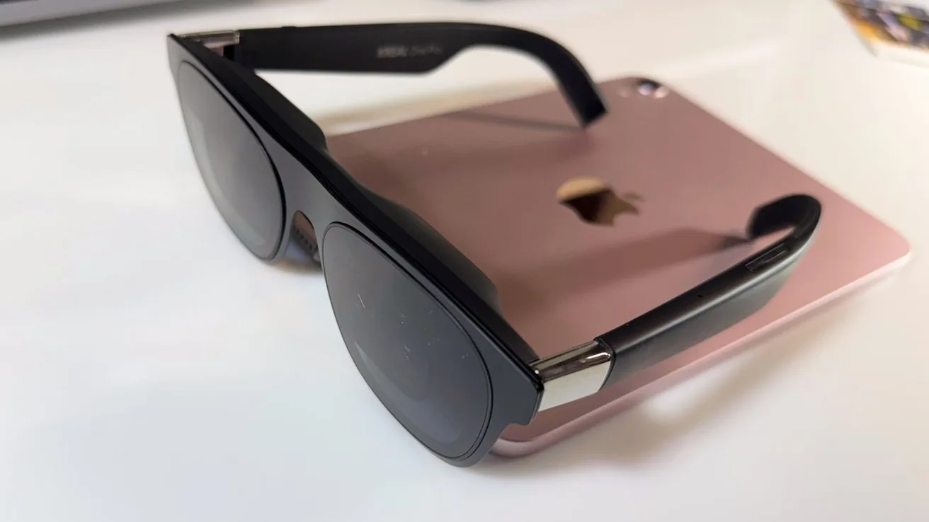 Black sunglasses resting on a rose gold tablet with a partially visible apple logo on a white surface.