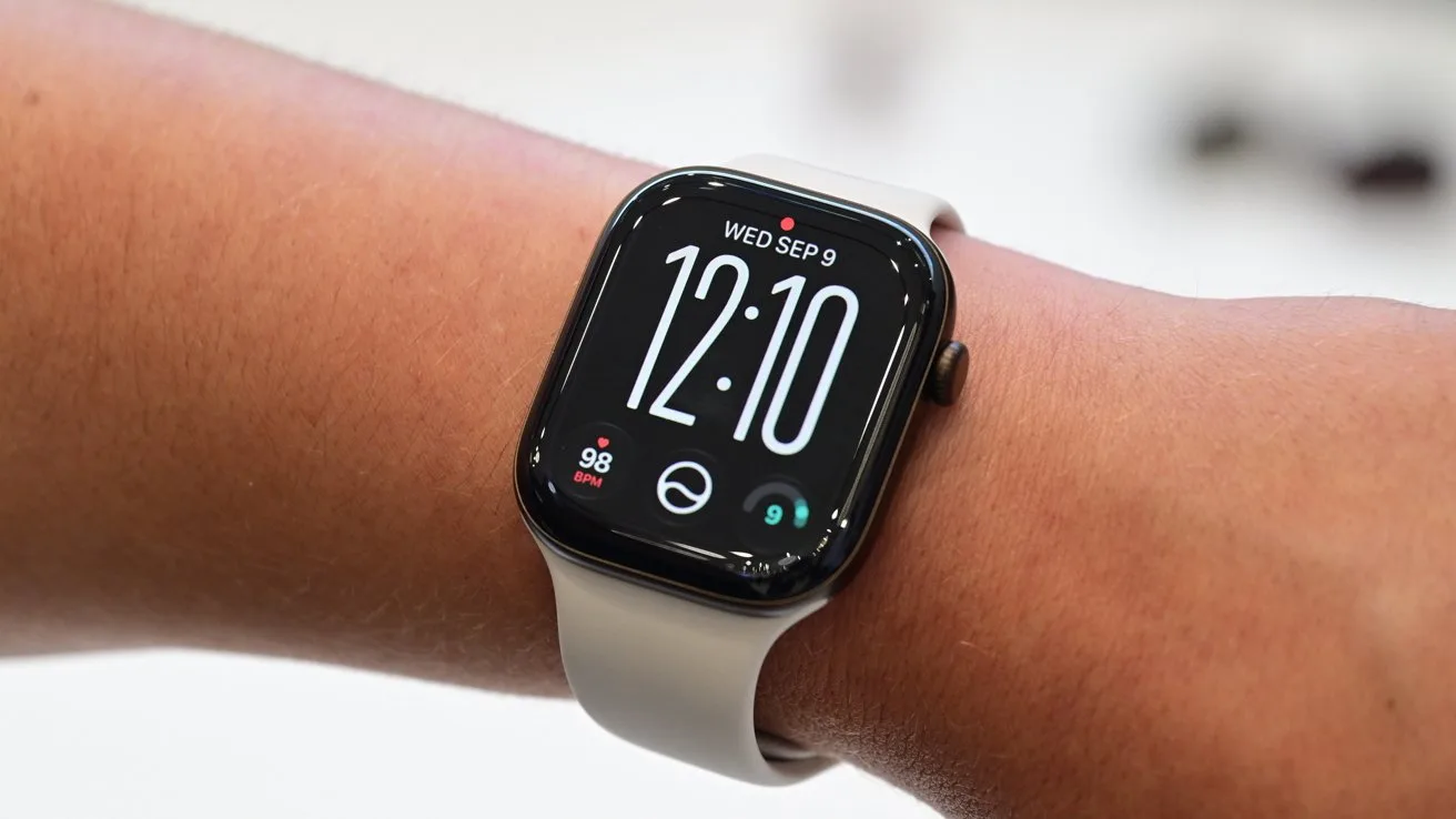 Close-up of a wrist wearing an Apple Watch with a rectangular screen, white band, and digital display showing time 12:10, date Wednesday September 9, and small health icons