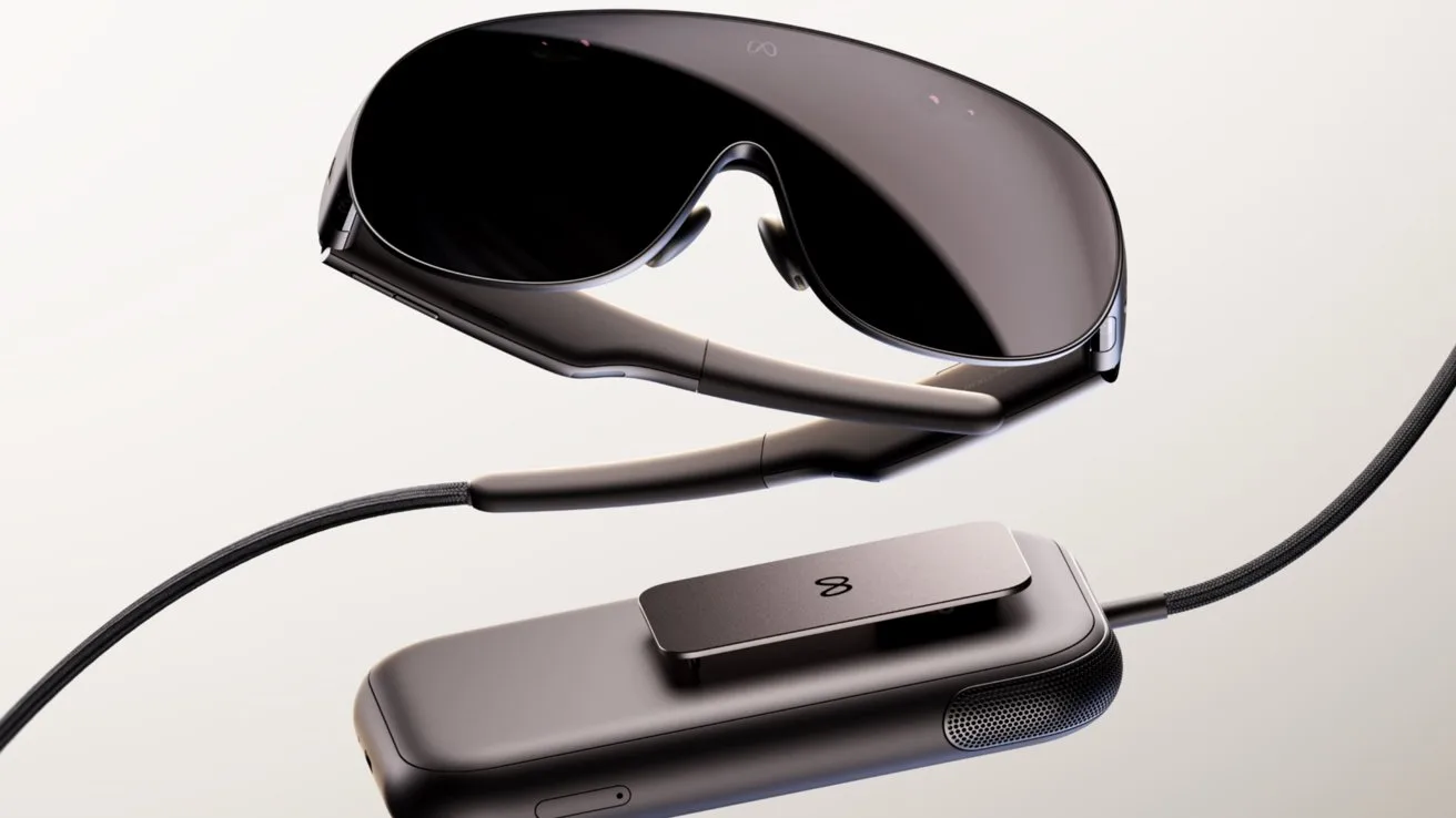 Sleek black augmented reality headset with large curved visor connected by cable to a slim rectangular controller, both resting on a light background