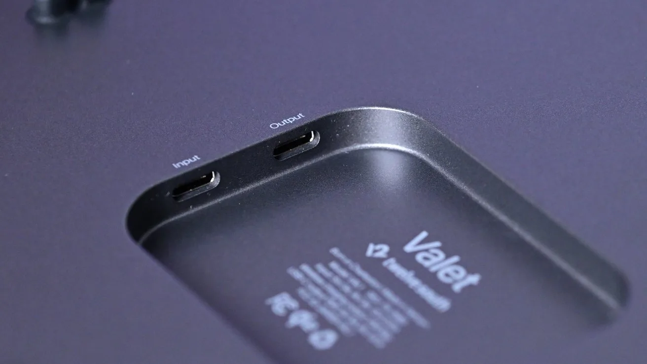 Close-up of a sleek electronic device labeled Valet with an inset area showing two USB-C style ports marked input and output on a smooth dark metallic surface