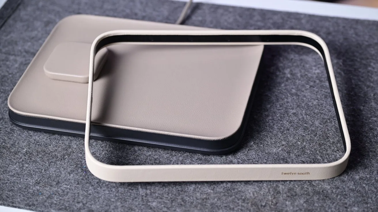 Rectangular beige wireless charging pad on a gray fabric surface, with a matching rectangular frame resting diagonally on top, showing minimalist modern design and smooth rounded edges