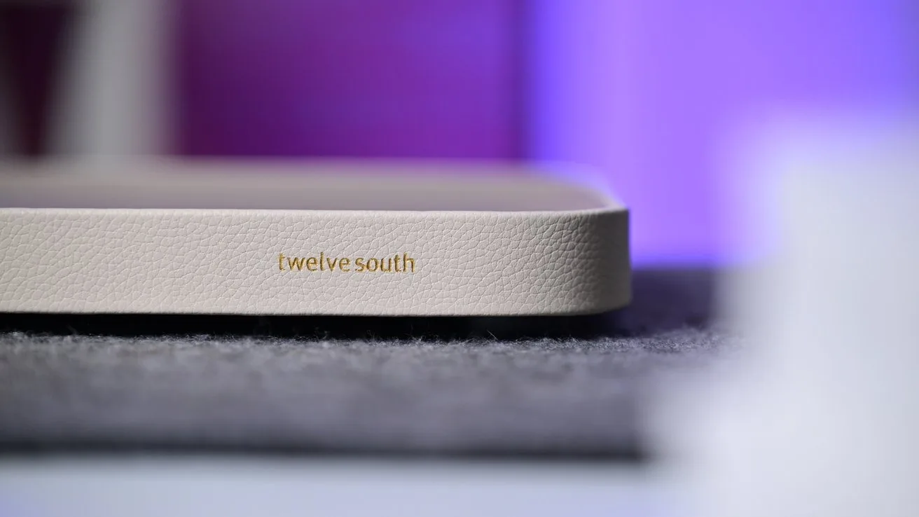 Close-up of a beige Twelve South device with textured surface, resting on a gray fabric mat against a softly blurred purple and blue background