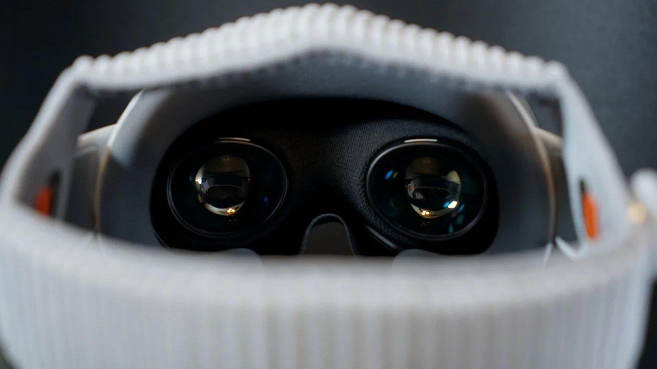 Close-up view of an Apple Vision Pro, focusing on its two reflective lenses framed by a white, textured head strap against a dark background