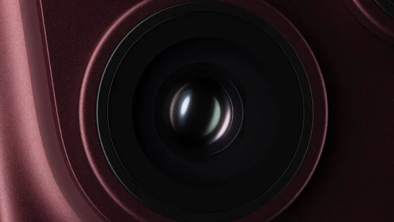 A close-up view of a dark red smartphone camera lens set within a circular housing.