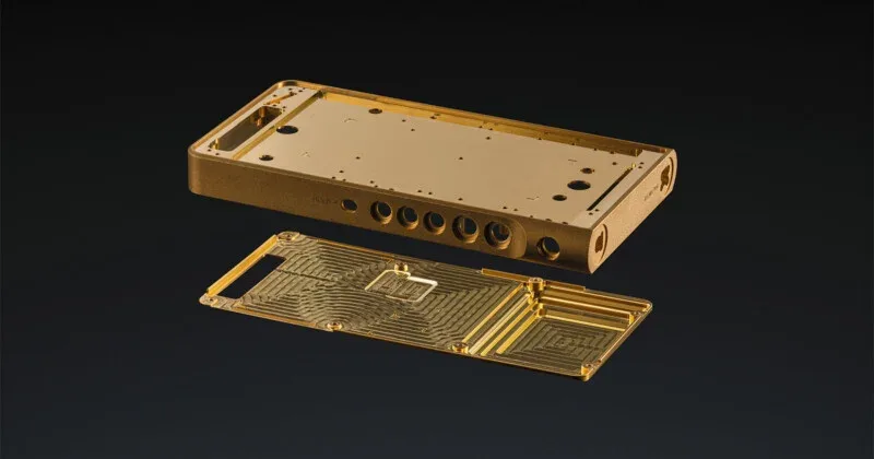 A disassembled gold-colored metal chassis for a portable electronic device, featuring a main housing with circular ports and a matching internal backplate with intricate milled patterns.