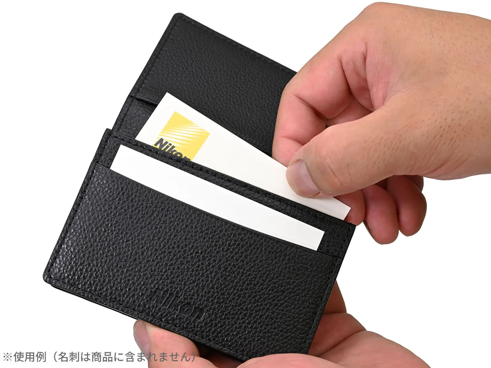 A pair of hands holds a black leather card holder containing a white business card with a yellow Nikon logo.