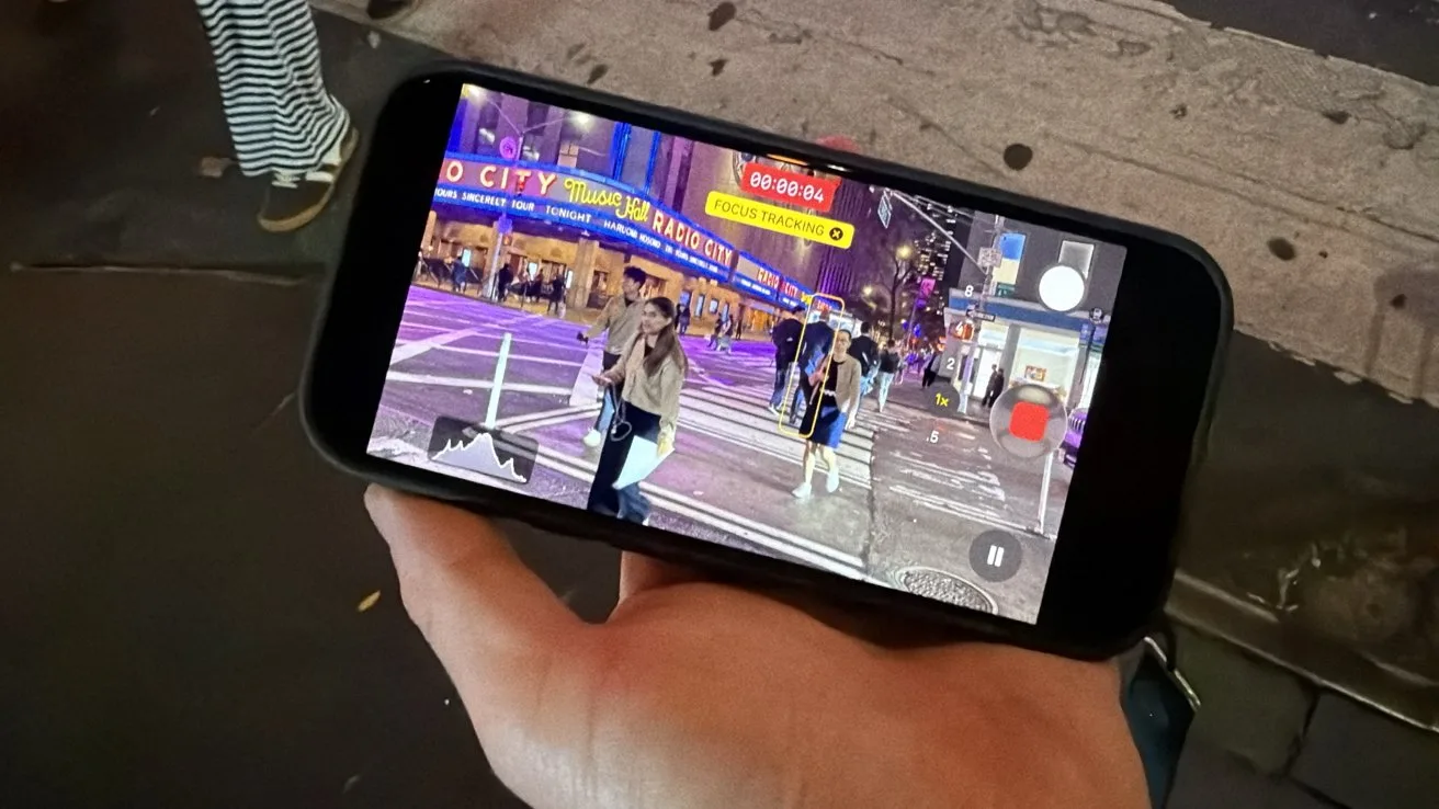 Hand holding a smartphone at night, displaying an augmented reality navigation view of a busy city street with pedestrians, crosswalk, neon storefronts, and directional labels.