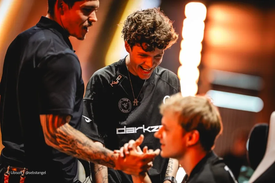 The photo features Rainbow Six Siege pro players from the team DarkZero — greeting each other on the stage of R6 Esports World Cup 2026 (EWC 2026), after a successful playoff match.