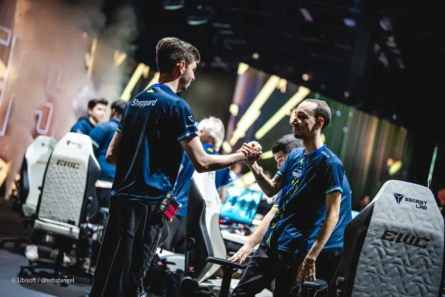The photo features Rainbow Six Siege pro players from the team Geekay Esports — greeting each other on the stage of R6 Esports World Cup 2026 (EWC 2026), after a successful playoff match.